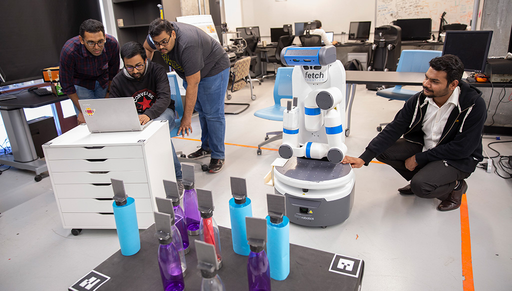 Students work on robotics research in a lab, with a robot positioned in front of colorful objects