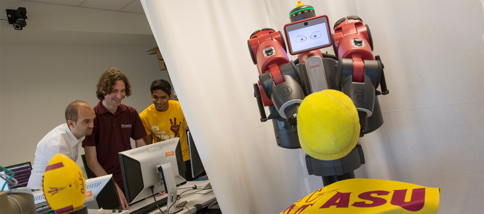 A robot grabs a tennis ball as students and faculty control it